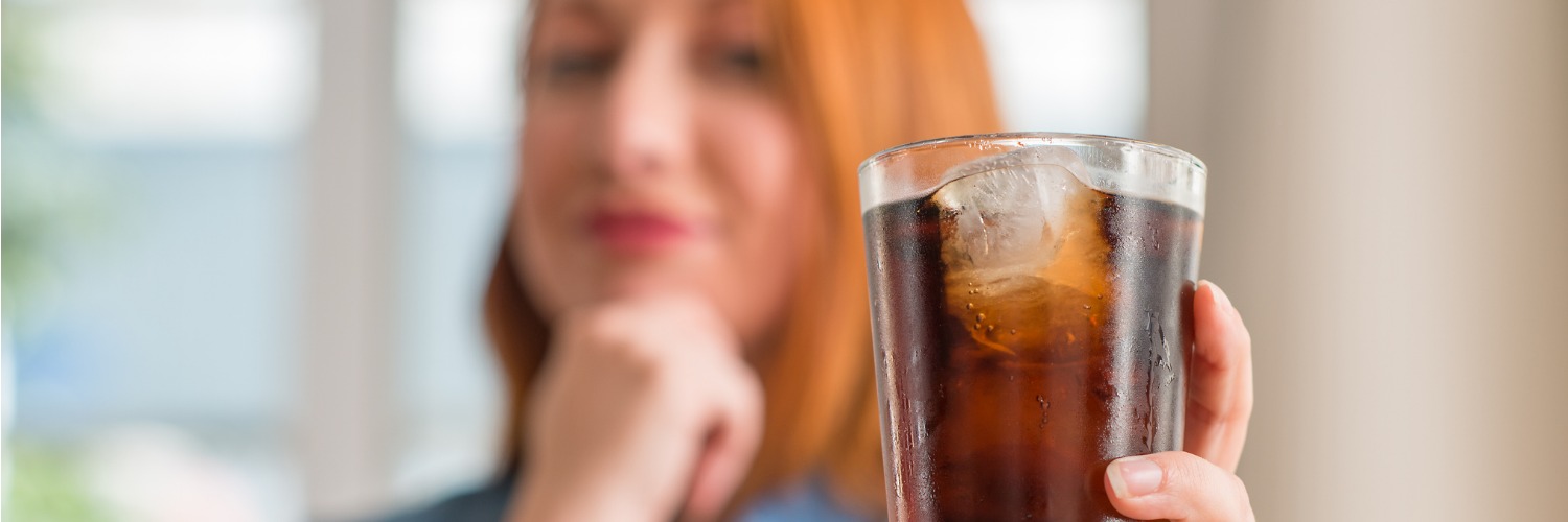 Wie viel Zucker braucht das Gehirn wirklich? Frau mit einem vollen Cola Glas